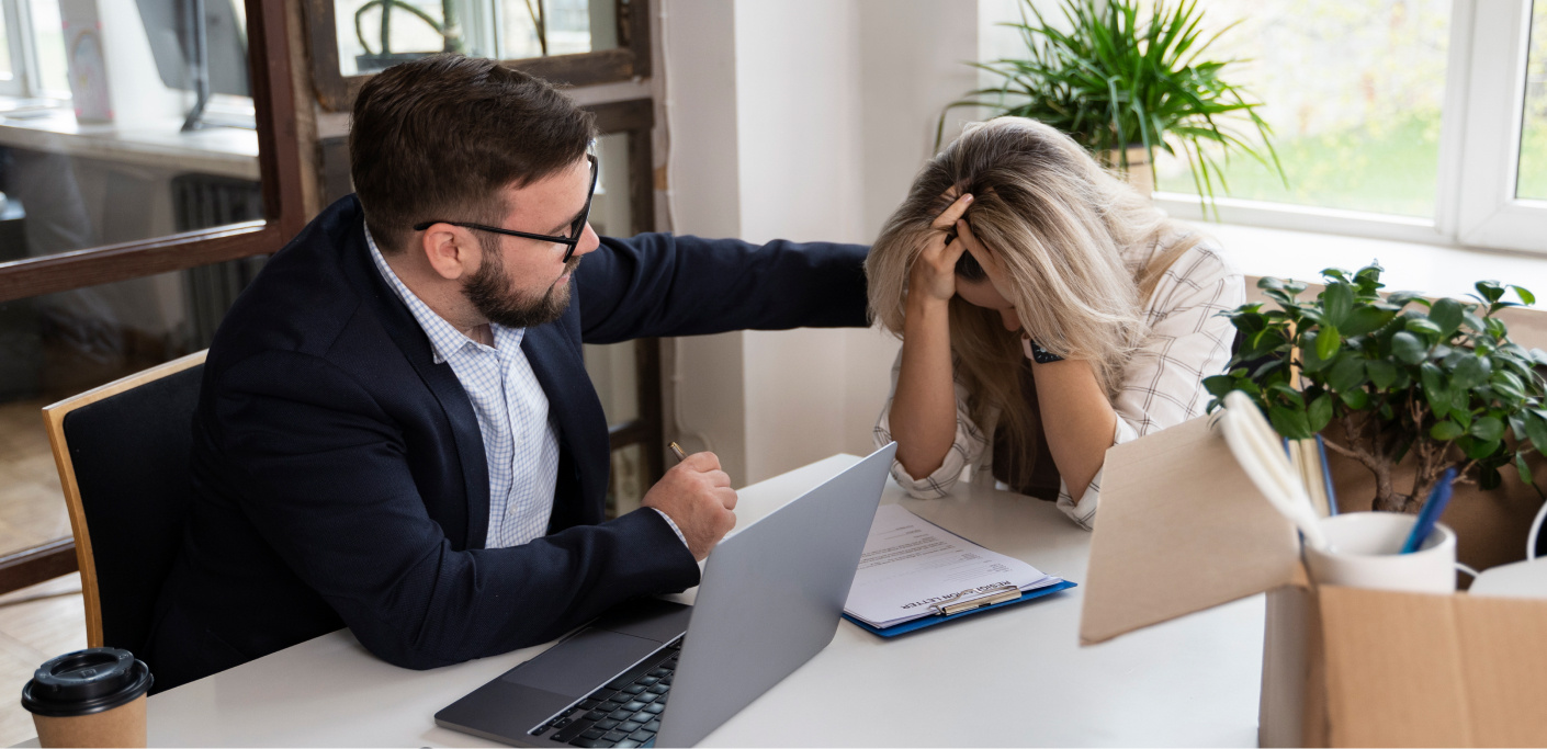 A man comforts a woman in an office environment