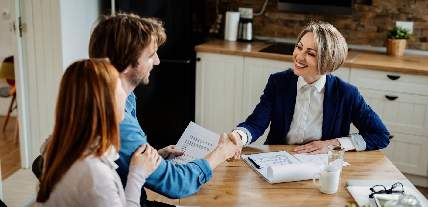 Couple shakes hands with property practitioner during a real estate deal