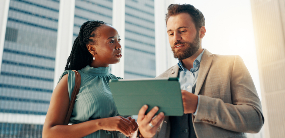 Sceptical woman looks at a male property practitioner as he uses a tablet