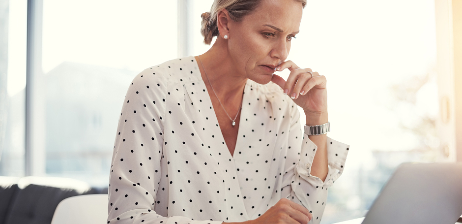Professional woman looks concerned as she views her laptop