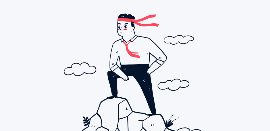 Man wearing a bandana stands on top of a rocky cliff