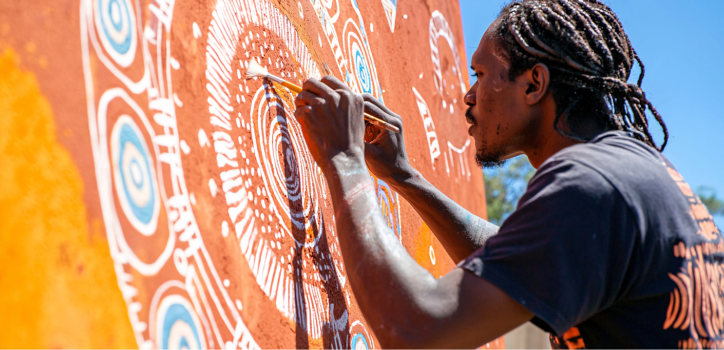 Male artist paints a mural on a wall in a township